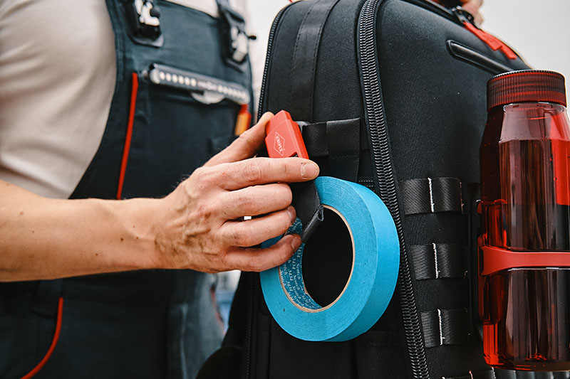 Befestigung einer Kleberolle und einer Trinkflasche an einem Rucksack