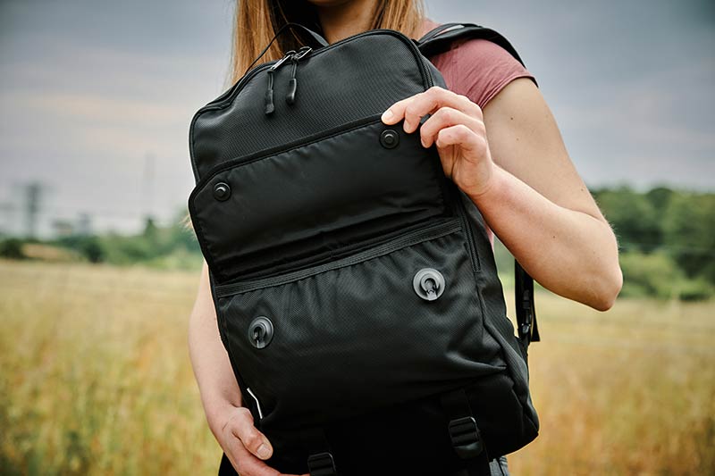 Woman opening black backpack with FIDLOCK buckles