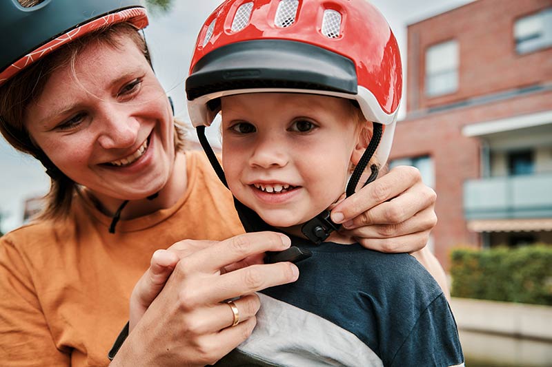 Woman closing helmet on child