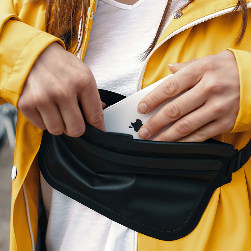 FIDLOCK-HERMETIC-sling-bag-schwarz-hände-die-ein.handy-reintun-outdoor